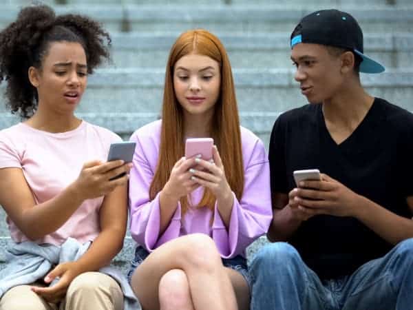 Students sitting together, each absorbed in their own phone